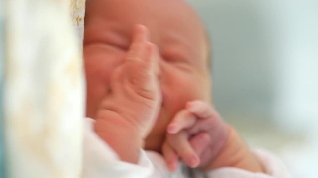 Restless sleep of a newborn kid. Small depth of field with focus on the hand