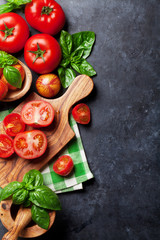 Fresh ripe garden tomatoes and basil on stone table