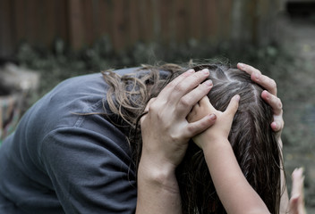 Woman sitting and with both hands holding his head. In the hands of a woman are the two hands of a...