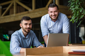 Fototapeta premium Picture of handsome businessman listening to his colleague or partner concerning ner business system while working on laptop computer in office interior.