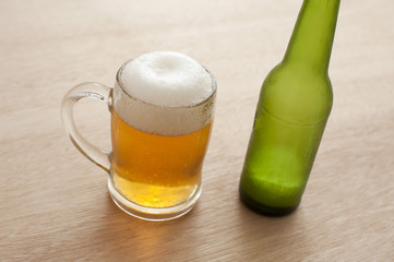Tankard of frothy beer with a bottle