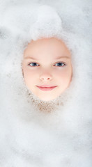delightful smiling face of a little girl in the foam