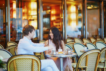 Couple drinking coffee and eating croissants in Parisian cafe