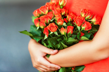 Fototapeta na wymiar Beautiful bright orange roses in child's hands