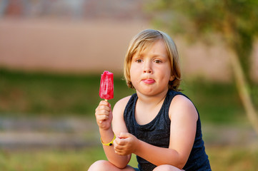 Cute little boy eating fruit homemade ice cream outdoors