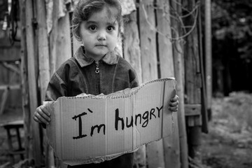 Little girl holding a sheet of cardboard. On the cardboard label 