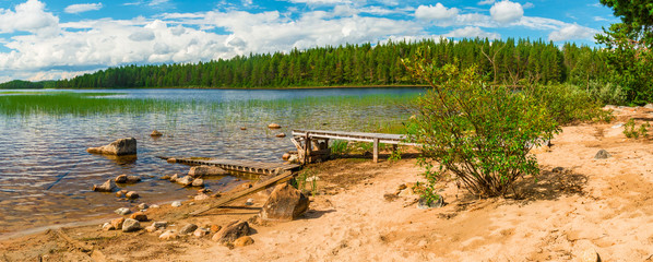 Panoramic view of the lake with pier and bush on the shore.