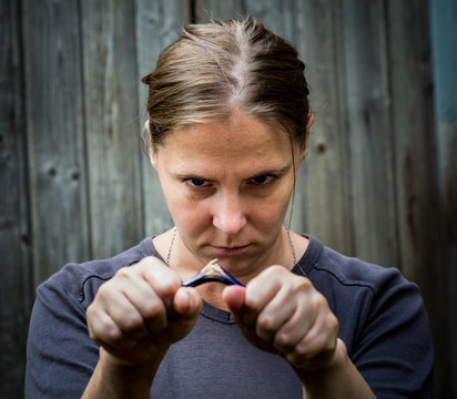 Woman with two hands holding broken pencil. face of a woman expresses anger.
