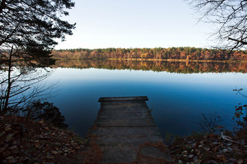 Old small wooden pier for fishing in autumn forest lake