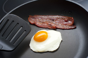 Frying egg and bacon for breakfast