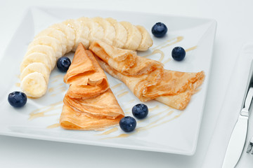 close up view of nice yummy crepes with banana on white