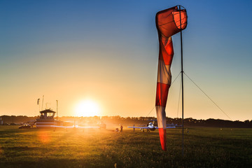 Airfield sign of the direction and force of the wind against airdrome and sunset background.