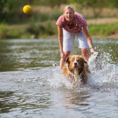 woman plays with her dog in the water