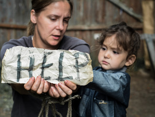 A woman with a child holding a sheet of paper. On a sheet of paper the word "help". The child pulls the rope.

