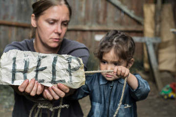 A woman with a child holding a sheet of paper. On a sheet of paper the word 