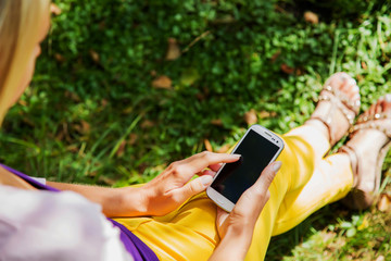 Young woman playing with mobile phone and resting in the park.