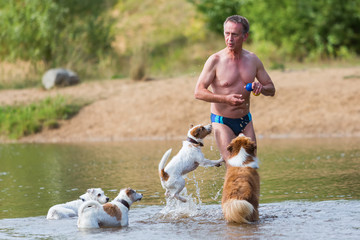 man plays with dogs in the river