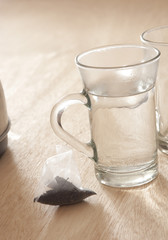 Tea Bag on Wooden Table Next to Mug of Hot Water
