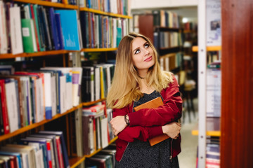 Female student choses a book in college library. Education concept