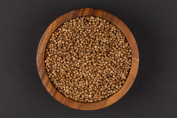 Coriander seeds in  small wooden bowl