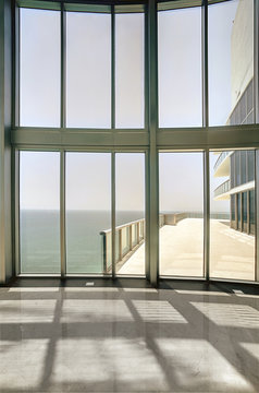 Empty room interior with floor to ceiling windows and ocean view