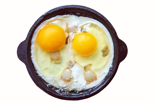 Two eggs and bacon in a cast iron skillet. Fried. Eggs. On a white background. An isolated object.