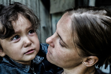 A woman holds a child, trying to calm him down. The child is three years.
