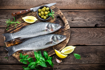 raw seabass fish on wooden background top view