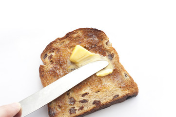 Person buttering a slice of raisin toast