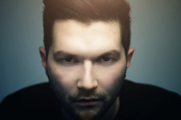 Serious hipster handsome man with evil eyes looking at you, close up studio portrait.