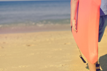 Young surfer with bodyboard having fun, sunny blue sky background