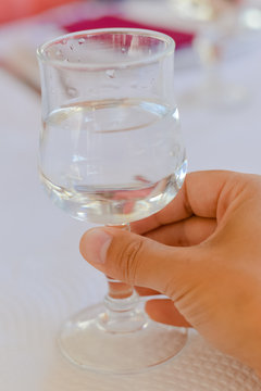Closeup view of human hand holding glass, restaurant light table background