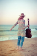 Defocused unrecognised person playing guitar on the beach background