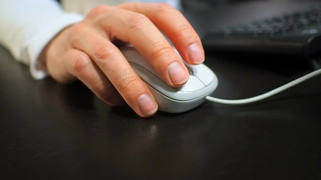 Mouse 12. Soft focus to hand of the man clicking right mouse button. Right hand from front right view.
