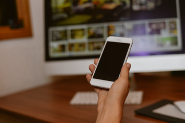 Top side view of a business person hands using smart phone, office desk background