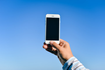Blue sky with person hand using touch smartphone, sunny background