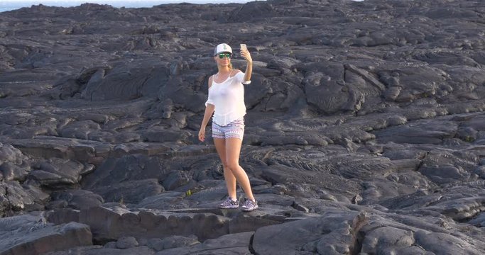Hiking Girl taking picture with lava in Kilauea volcano Hawaii. Tourist taking photo of lava from Kilauea volcano around Hawaii volcanoes national park, USA.
