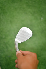 Choosing holding golf club in hand, close up view, defocused background