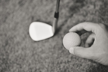 Close up view of person hand holding golf ball club on green grass background