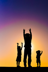 Beautiful sunset silhouette of father with kids, outdoors background