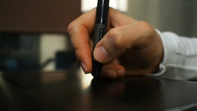 Tablet 19. Close up of the hand of a graphic designer holding an electronic stylus. Left view.