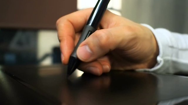 Tablet 20. Close up of the hand of a graphic designer clicking button on electronic stylus like middle mouse button. Left view.