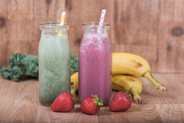 Two smoothie shakes in milk bottles with fresh fruit