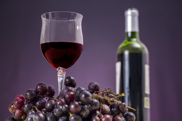 Glass of Rioja wine beside red grapes, in front of a wine bottle