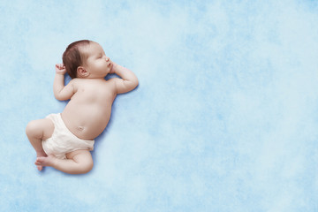Newborn baby sleeps on blue background. Child's portrait. Place for your design.
