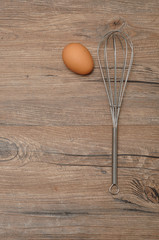 An egg beater, whisk, with one egg 