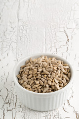 Shelled sunflower seeds in bowl on rustic white table