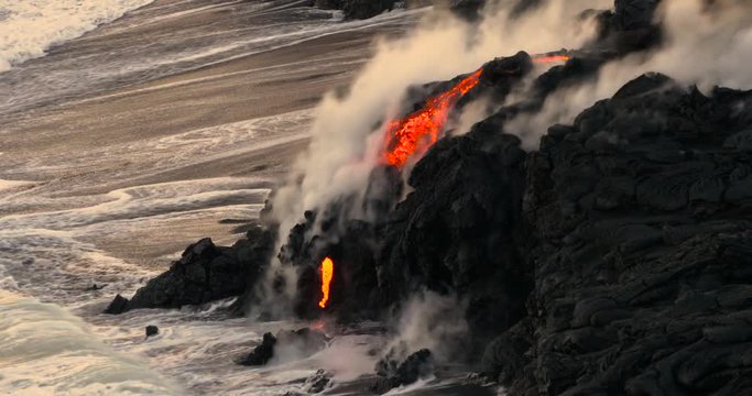 Volcanic Eruption Lava flowing into the water Hawaii. Steam rising from waves as molten lava flows into ocean waters Big Island Hawaii.