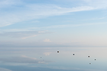 Evening sunlight on coast, pink clouds, blue sky reflection on water.  Beach in summer. Seaside natural environment. Shore in Osmussaar Island, Nature Reserve in Estonia, National Park in Europe
