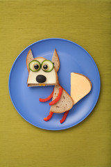 Squirrel made of bread and vegetables on plate and fabric
